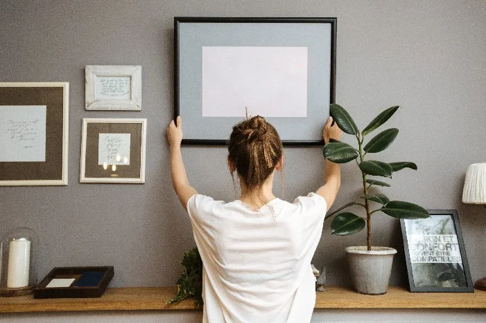 Person bringt Bilderrahmen an